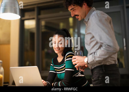 Paar mit Laptop, Wein trinken und zu Hause Stockfoto