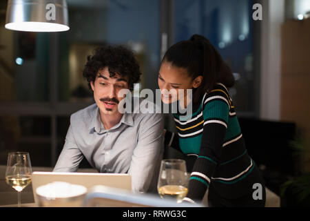 Paar mit Laptop und trinken Wein zu Hause in der Nacht Stockfoto