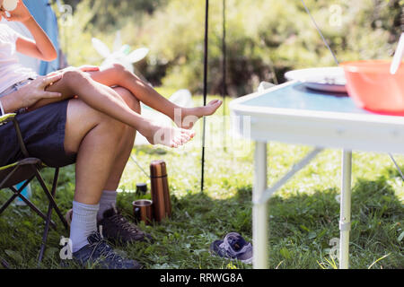 Beine von Vater und Tochter am Campingplatz Stockfoto