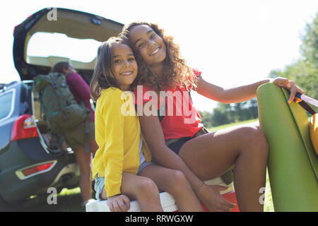 Portrait happy Schwestern Camping, Auto entladen Stockfoto