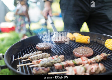 Man grillen Hamburger, Döner und Maiskolben Stockfoto