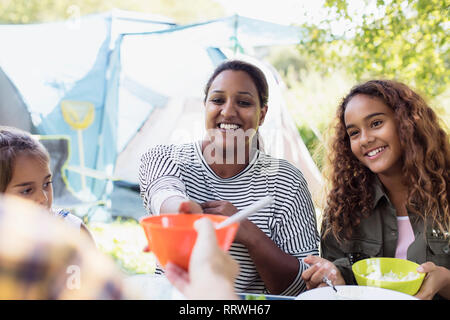 Lächelnde Mutter und Töchter Mittagessen auf dem Campingplatz Stockfoto