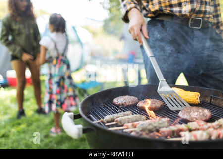 Man grillen Hamburger, Döner und Maiskolben Stockfoto