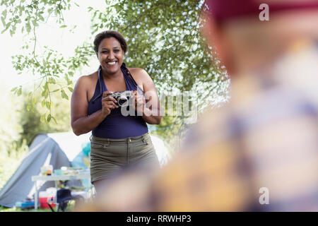 Glückliche Frau mit Kamera auf dem Campingplatz Stockfoto