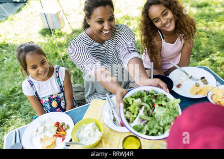 Glückliche Mutter und Töchter genießen Salat Mittagessen auf einem Campingplatz Tabelle Stockfoto