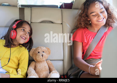 Glückliche Schwestern und Teddybär Reiten in Rücksitz des Autos Stockfoto