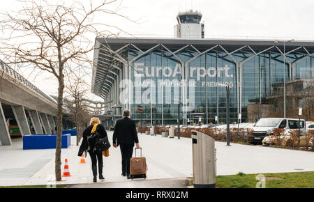 BASEL, SCHWEIZ - 22.MÄRZ 2018: Pendler Paar zu Fuß in Richtung EuroAirport Basel Mulhouse Freiburg Glasfassade - großem Betrachtungswinkel Stockfoto