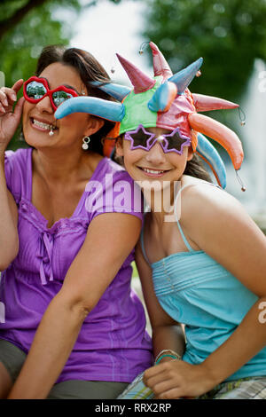 Lächelnde Mutter und Tochter tragen Neuheit Hüte und Sonnenbrillen. Stockfoto