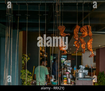 Hähnchenschenkel hängend auf Spieße in einem indischen Restaurant Stockfoto