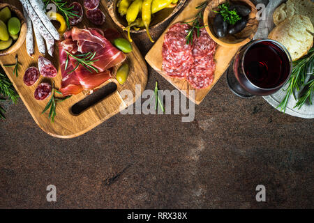 Antipasti - geschnittenes Fleisch, Schinken, Salami, Oliven auf dunklem Stein Tabelle Ansicht von oben. Stockfoto