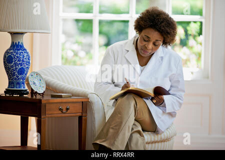 Reifen Therapeuten Schreiben in ein Notizbuch, wenn sie alleine in ihrem Büro. Stockfoto