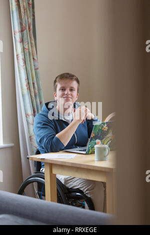 Portrait selbstbewussten jungen Frau im Rollstuhl mit Laptop am Esstisch Stockfoto