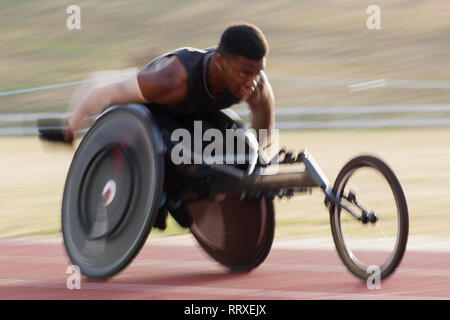 Bestimmt jungen männlichen querschnittsgelähmten Athlet Beschleunigung zusammen Sport Track im Rollstuhl Rennen Stockfoto