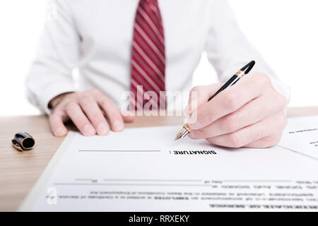 Geschäftsmann in Hemd und Krawatte ein Papier unterzeichnen Vertrag mit einem Kugelschreiber auf dem Schreibtisch Stockfoto