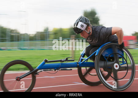 Entschlossene junge weibliche paraplegic Athlet Beschleunigung zusammen Sport Track im Rollstuhl Rennen Stockfoto