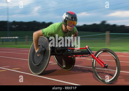 Bestimmt jungen männlichen querschnittsgelähmten Athlet Beschleunigung zusammen Sport Track im Rollstuhl Rennen Stockfoto