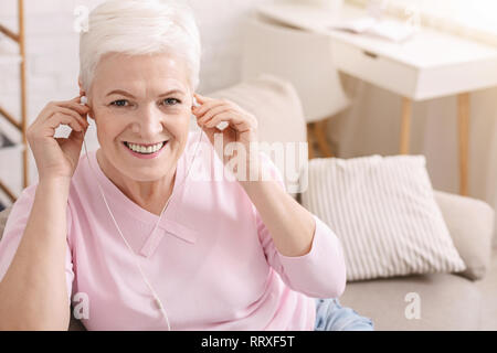 Freuen gealterte Frau um zu Hause Musik hören Stockfoto