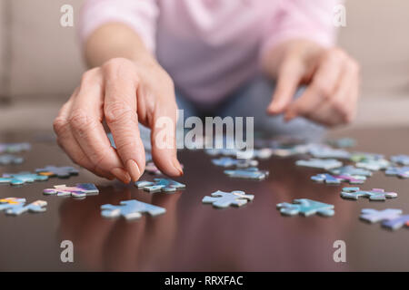 Ältere Frau Hände tun Puzzle closeup Stockfoto