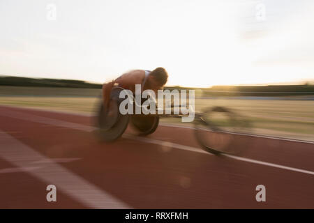 Bestimmt jungen männlichen querschnittsgelähmten Athlet Beschleunigung zusammen Sport Track im Rollstuhl Rennen Stockfoto