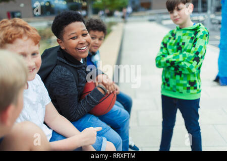 Happy tween Jungen mit Basketball in Schulhof Stockfoto