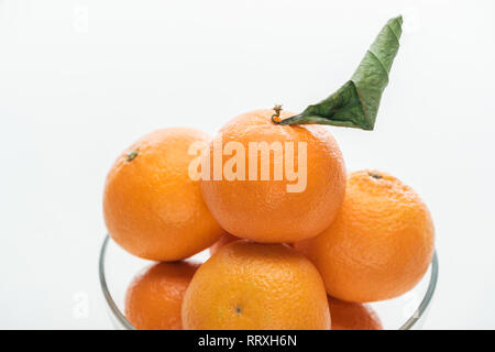 Nahaufnahme der Mandarinen Stapel in Glasschale auf weißem Hintergrund Stockfoto