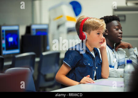 Fokussierte Junior High School Junge mit Kopfhörern im Klassenzimmer Stockfoto