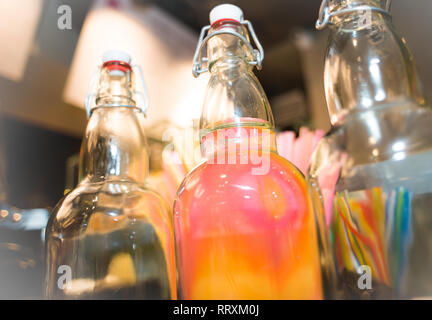 Flaschen mit bunten Drinks an der Bar stehen Stockfoto