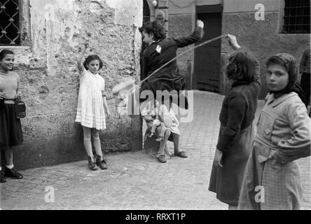 Reisen nach Rom - Italien 1950 s - springen roping Kinder auf einer kleinen Gasse in Rom. Mädchen beim Seilspringen in einem Hinterhof in Rom, Italien. Foto Erich Andres Stockfoto