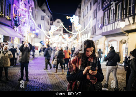 Straßburg, Frankreich - 29.November 2017: Junge Frau Smartphone verwenden als Besucher bewundern Sie die wunderschön dekorierten Straßen von Straßburg, Weihnachten Kapital in Europa Stockfoto