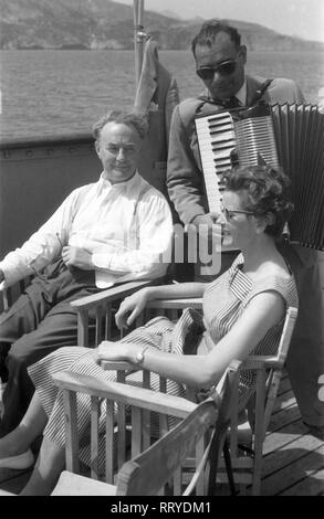 Spanien, Griechenland - Ein Mann und eine Frau werden ein Bord your Kreuzfahrtschiffes vom Musikanten unterhalten, Spanien 1950er Jahre. Ein Mann und eine Frau werden von einem musicain an Bord ihres Kreuzfahrtschiffes, Griechenland unterhalten, 1950er Jahre. Stockfoto