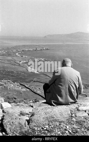 Spanien, Griechenland - Ein Mann sitzt oberhalb der Tempelruine von Ialyssos in Rhodos und schaut auf das Meer und die Nachbarinseln, Panorama, 1950er Jahre. Ein Mann sitzt über dem Tempel Ruinen von Ialyssos und Uhren die umliegende Landschaft, Rhodos, Griechenland, 1950. Stockfoto