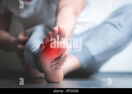 Causian Mann hält Hände an seine schmerzende Füße, Schmerzen im Fuß. Die rote Farbe wird der Schmerz Stockfoto