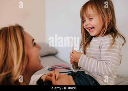 Cute girl Holding Zungenspatel beim Gespräch mit Ihrem Arzt. Mädchen ihren Kinderarzt für Hals Checkup besuchen. Stockfoto