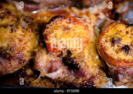 Appetitliche leckere Kalorienarme Diät juicy Hähnchenschenkel gewürzt mit Tomate und bestreut mit geriebenem Käse überbacken im Ofen braten im eigenen Saft Stockfoto