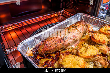 Appetitliche leckere Kalorienarme Diät juicy Hähnchenschenkel gewürzt mit Tomate und bestreut mit geriebenem Käse überbacken im Ofen braten im eigenen Saft Stockfoto