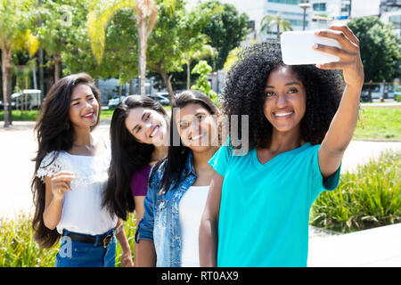 Afrikanische amerikanische Frau, die selfie mit Telefon und internationalen Freundinnen Outdoor im Sommer in der Stadt Stockfoto