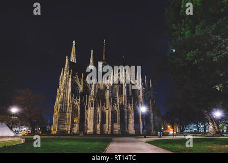 Wien, Österreich - 25. Dezember 2017. Neo-gotischen Twin Tower Votivkirche bei Nacht beleuchtet mit keine Menschen. Fassade der gotischen Votivkirche, Bäume ein Stockfoto