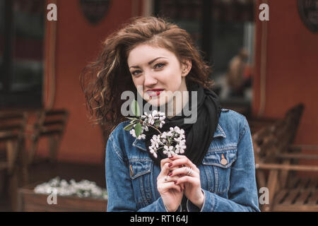 Schöne junge Frau mit lila Zweig stehen auf Stadt. Stockfoto