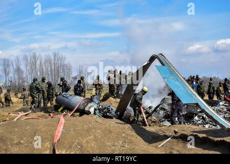 Budgam, Kaschmir. 27. Februar, 2019. Ein Feuerwehrmann spritzt Wasser in den Trümmern eines indischen militärische Flugzeuge, die in Budgam, 20 km von Srinagar, Kashmir abgestürzt. Eine indische Luftwaffe stürzte am Mittwoch in Budgam Bezirk von Kaschmir, die Tötung von sieben Personen, darunter sechs indische Luftwaffe Personal und ein Zivilist. Das Flugzeug aus technischen Gründen abgestürzt, sagten Beamte. Credit: Saqib Majeed/SOPA Images/ZUMA Draht/Alamy leben Nachrichten Stockfoto