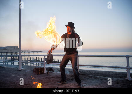Aberystwyth Wales UK Mittwoch, den 27. Februar 2019. UK Wetter: ein Mann Jonglieren mit Feuer an der Promenade Aberystwyth, wie die Sonne, die die meisten der sensationell heiß und sonnig, 'Winter' Wetter, während es dauert. Das Wetter Prognose zu starten ab morgen zu verschlechtern, mit mehr typische windig und kühler Anfang März Foto Keith Morris/Alamy Live Nachrichten erwartet Stockfoto