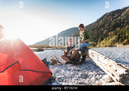 Reifes Paar camping am Flußufer im Abendlicht Stockfoto