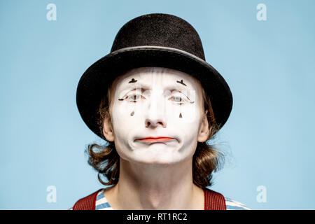 Nahaufnahme Porträt eines Schauspielers als Pantomime mit weißem Gesicht Make-up zeigt ausdrucksstarke Emotionen auf den blauen Hintergrund Stockfoto