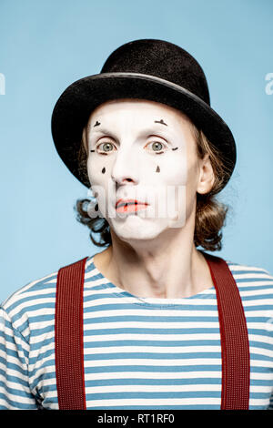 Nahaufnahme Porträt eines Schauspielers als Pantomime mit weißem Gesicht Make-up zeigt ausdrucksstarke Emotionen auf den blauen Hintergrund Stockfoto