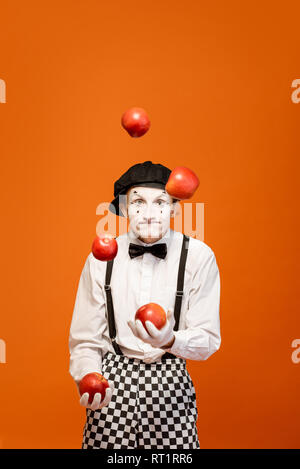 Porträt eines Schauspielers als Pantomime mit weißem Gesicht Make-up zeigt ausdrucksstarke Emotionen auf dem orangen Hintergrund im Studio Stockfoto