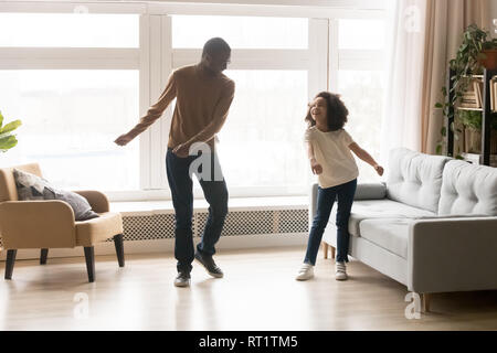 Happy afrikanischen Vater und Kind Tochter tanzen im Wohnzimmer. Stockfoto