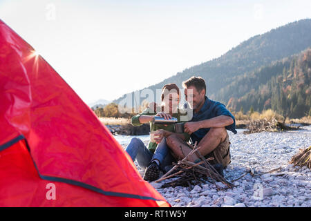 Reifes Paar camping am Flußufer im Abendlicht Stockfoto