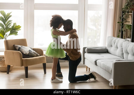 Zärtlich liebende schwarze Vater umarmt Kid stehendes Mädchen auf Knie Stockfoto