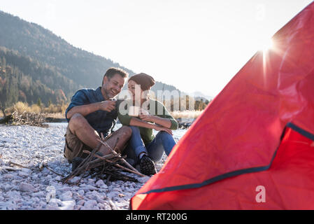 Reifes Paar camping am Flußufer im Abendlicht Stockfoto