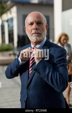 Senior Geschäftsmann seine Krawatte einstellen mit Geschäftsfrau im Hintergrund Stockfoto