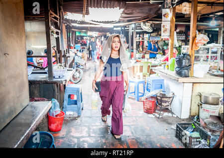 Eine junge Dame macht sich auf den Weg durch einen beengten, geschäftigen Hallenmarkt in Phnom Penh, Kambodscha. Stockfoto